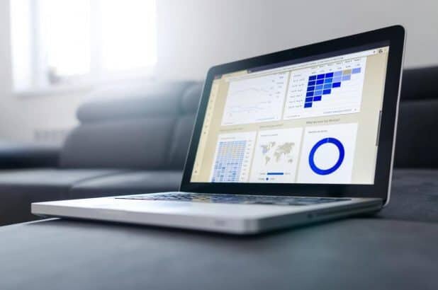 A laptop on a gray couch, displaying metrics and graphs.